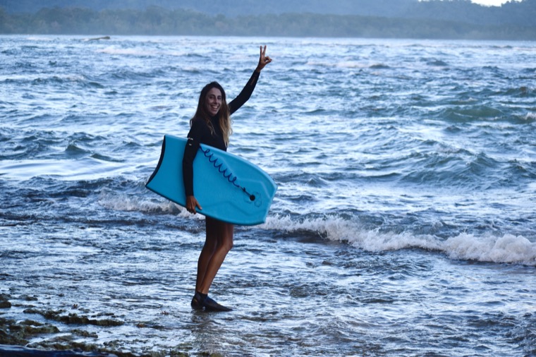 Anne-Cécile smiles with her bodyboard by the ocean.