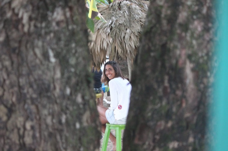 Anne-Cécile smiling between palm trees.
